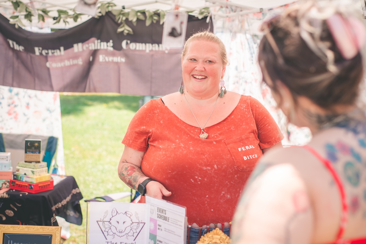 woman in orange greets customer at faire