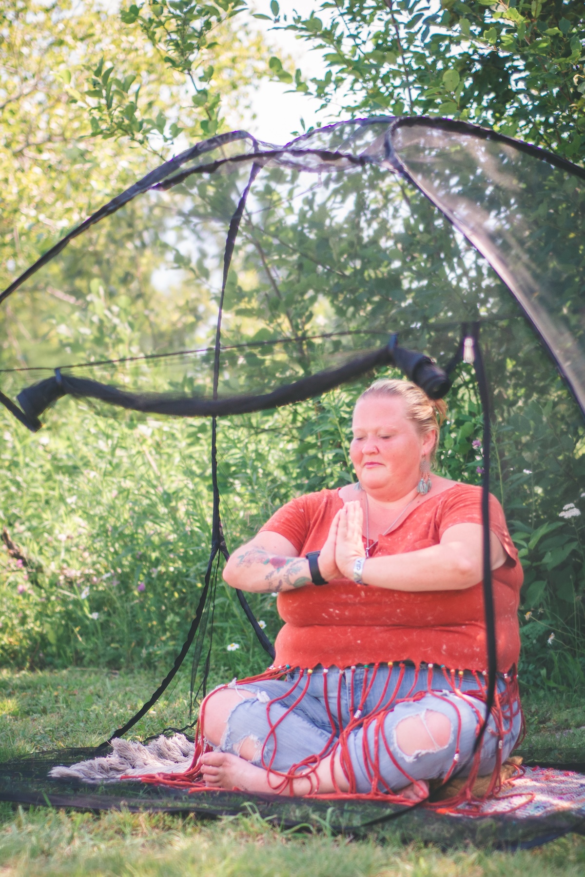 woman meditates in a mesh tent