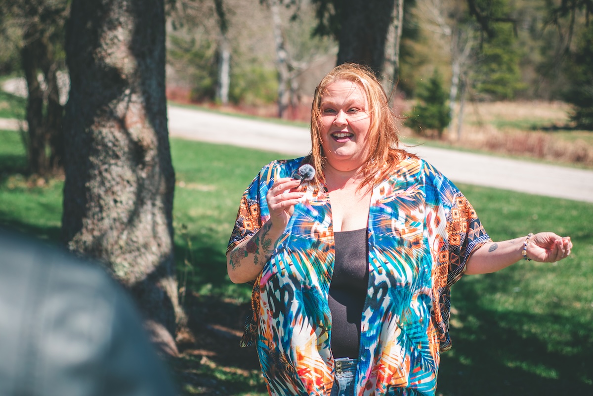 woman holds microphone and talks to audience outdoors