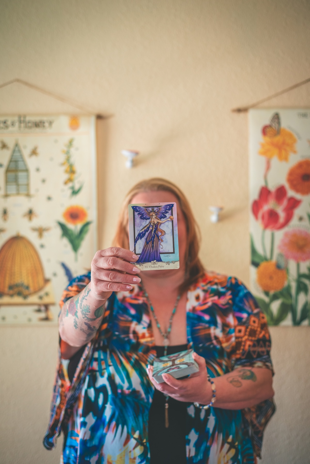 woman holds tarot card in front of her face