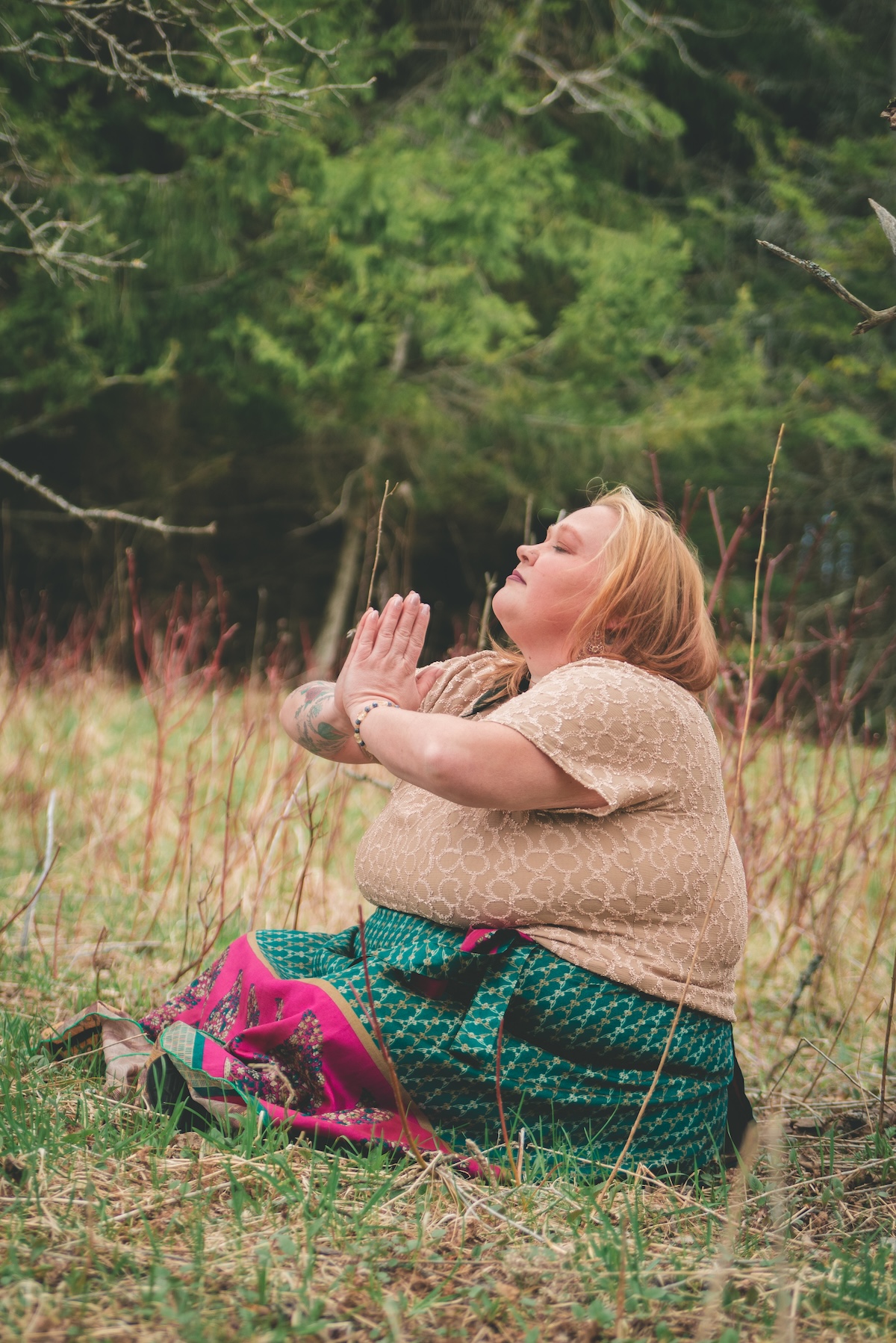 woman in green skirt meditates in a field
