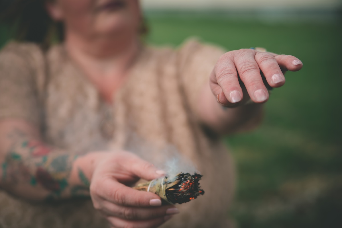 woman smudges her hands with sage