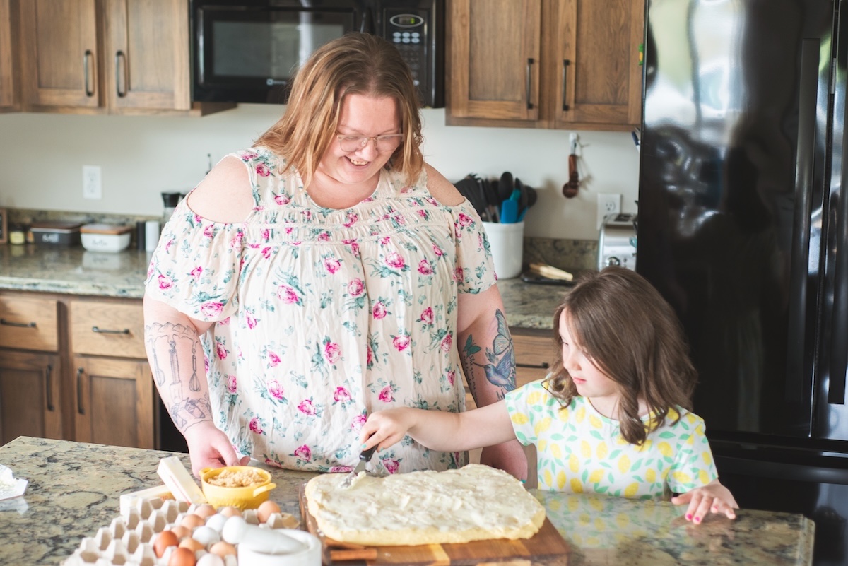 mom and daughter butter their homemade cinnamon rolls