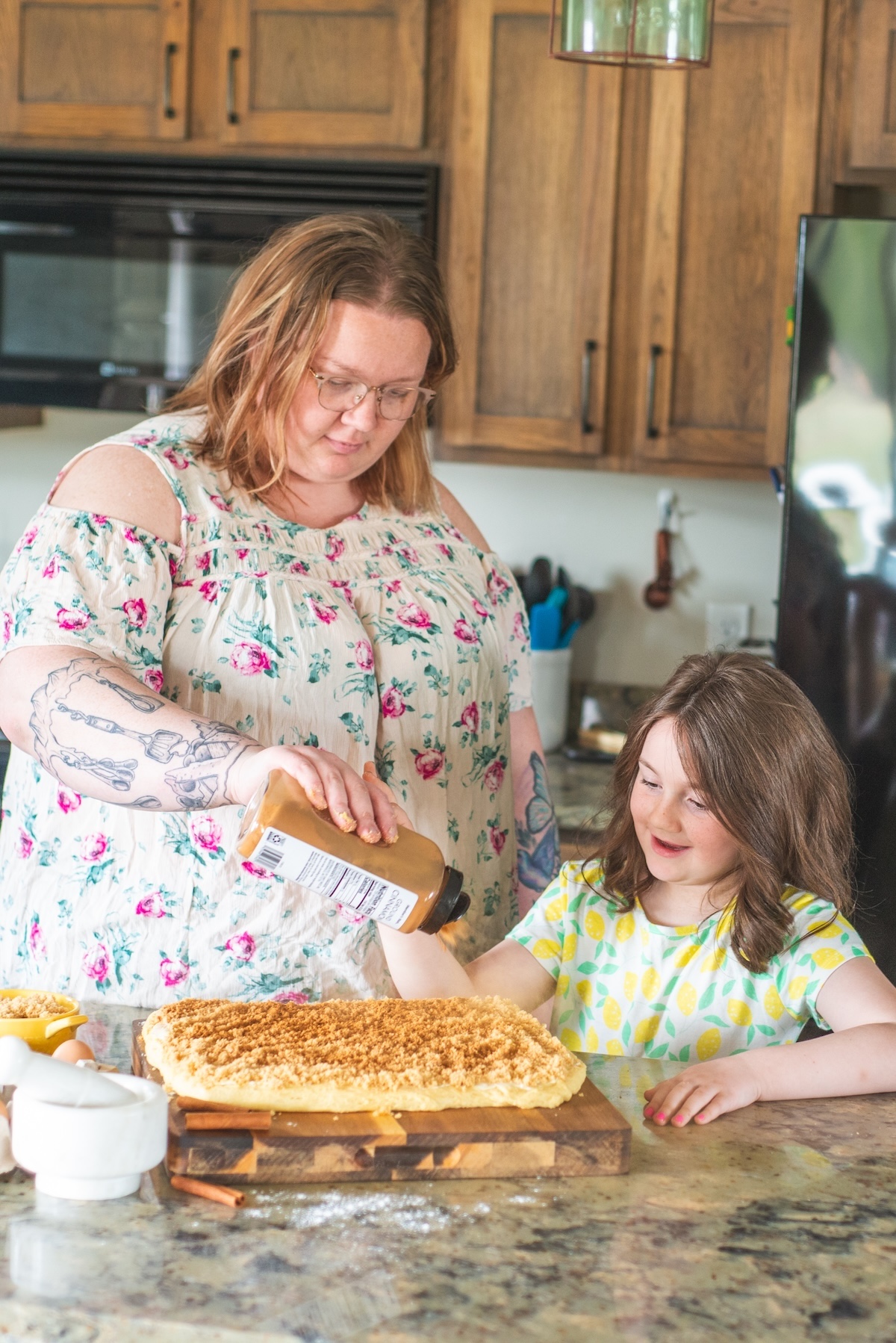 mom and daughter adding cinnamon ingredient to cinnamon rolls in kitchen