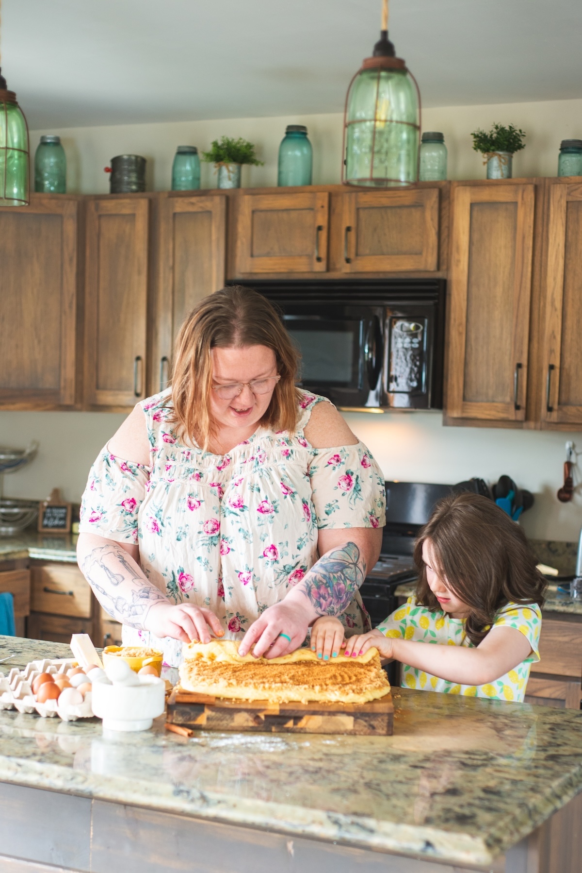 mom and daughter rolling cinnamon rolls in kitchen