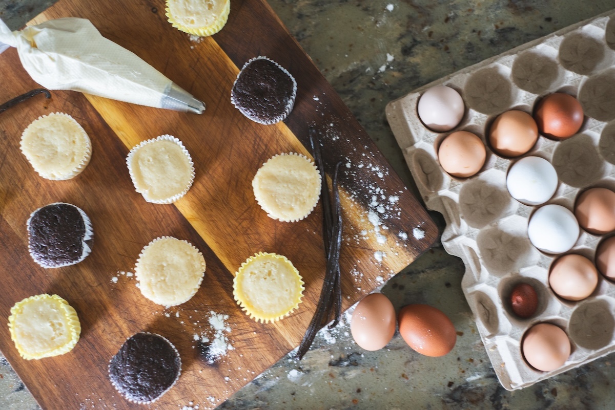 flat lay of piping bag, unfrosted cupcakes, and eggs on cutting board
