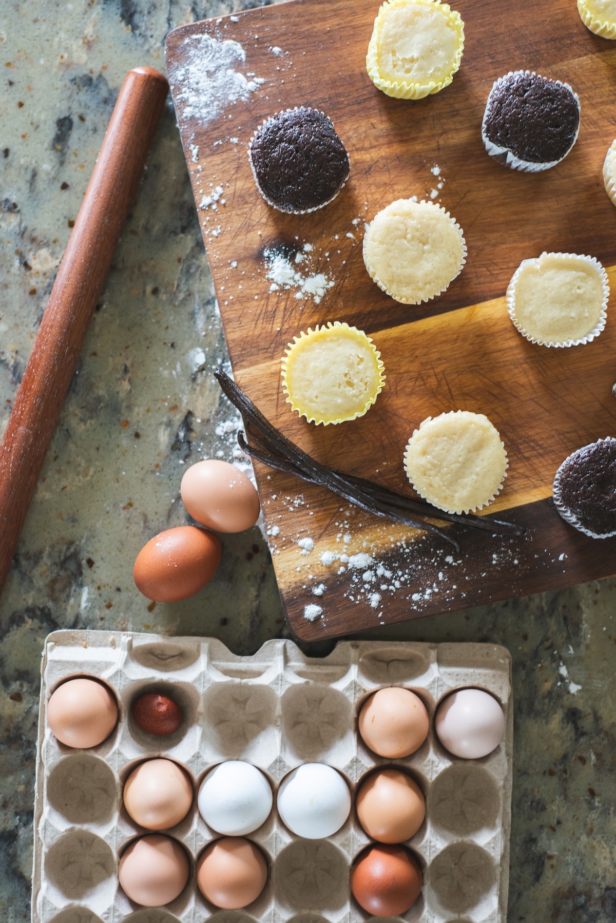 flay lay of eggs, vanilla bean, and unfrosted cupcakes