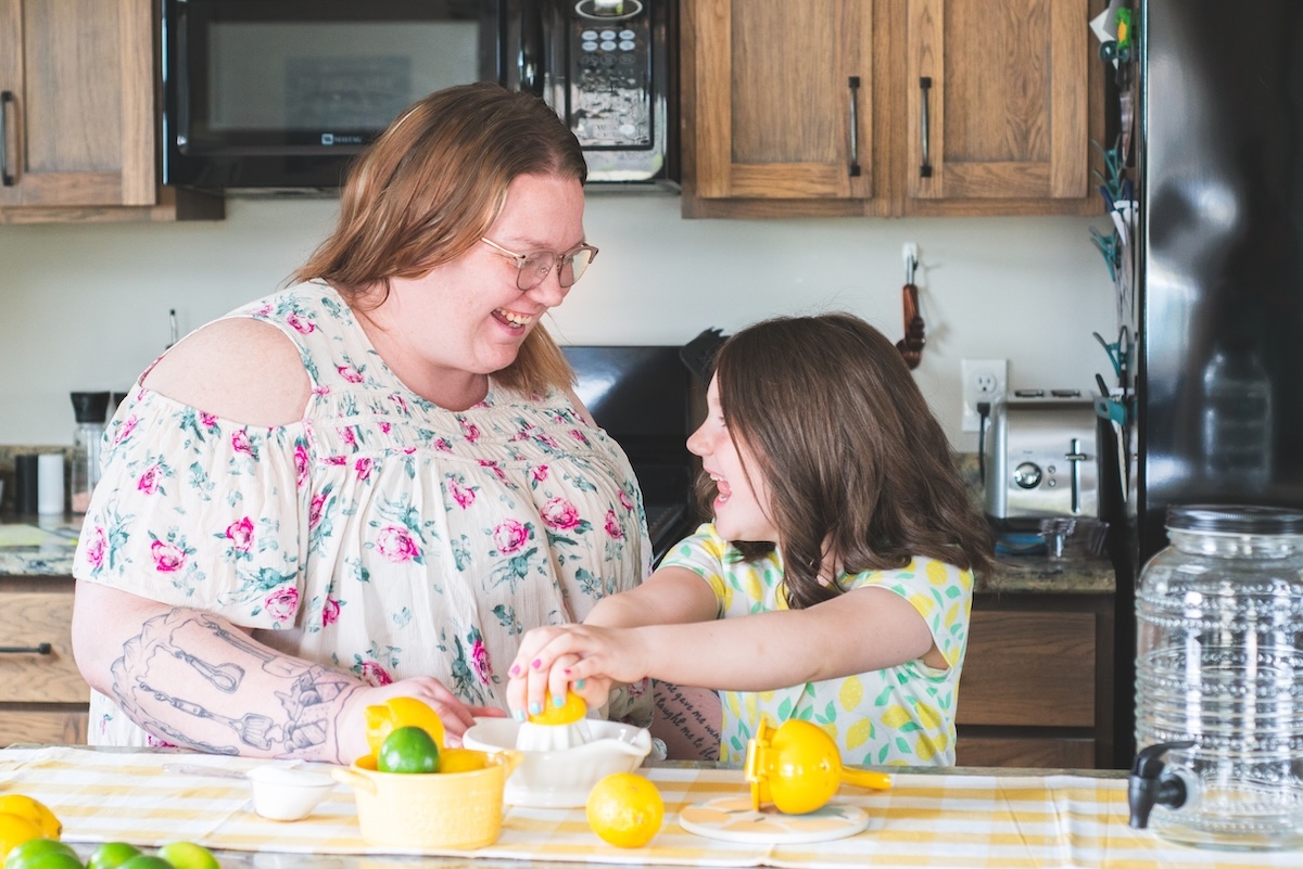 mom and daughter laugh while making lemonade at home