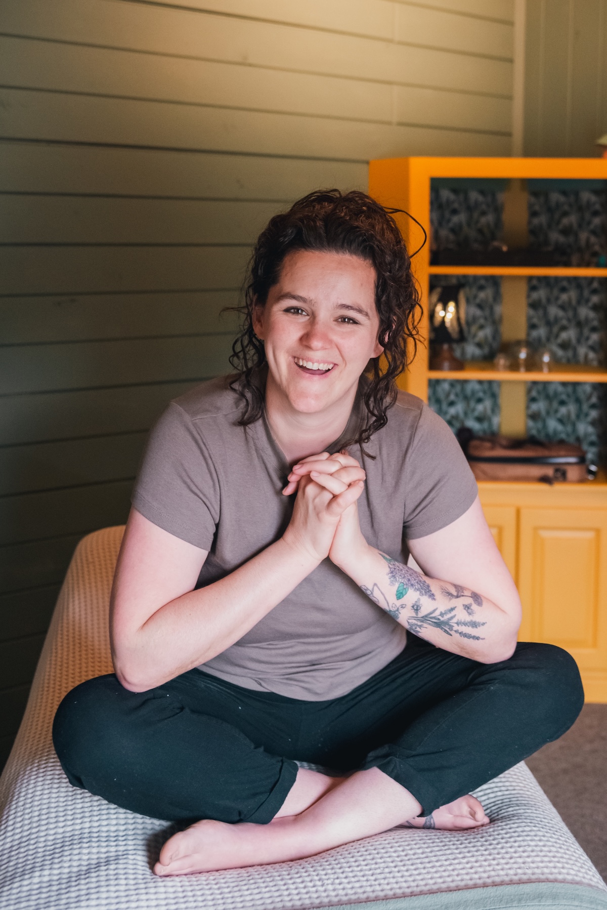 massage therapist sits cross legged on massage table