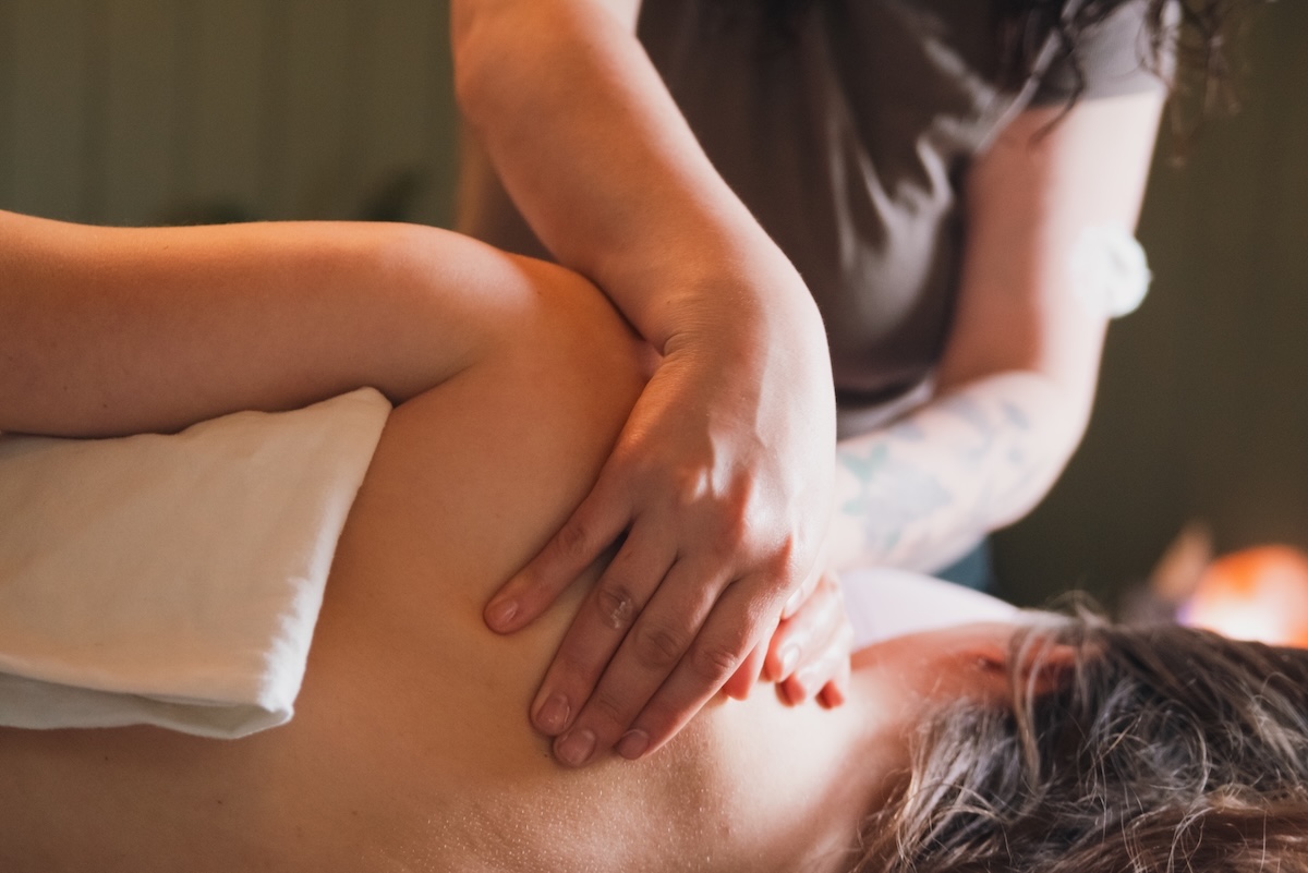 massage therapist works on a knot on the shoulder