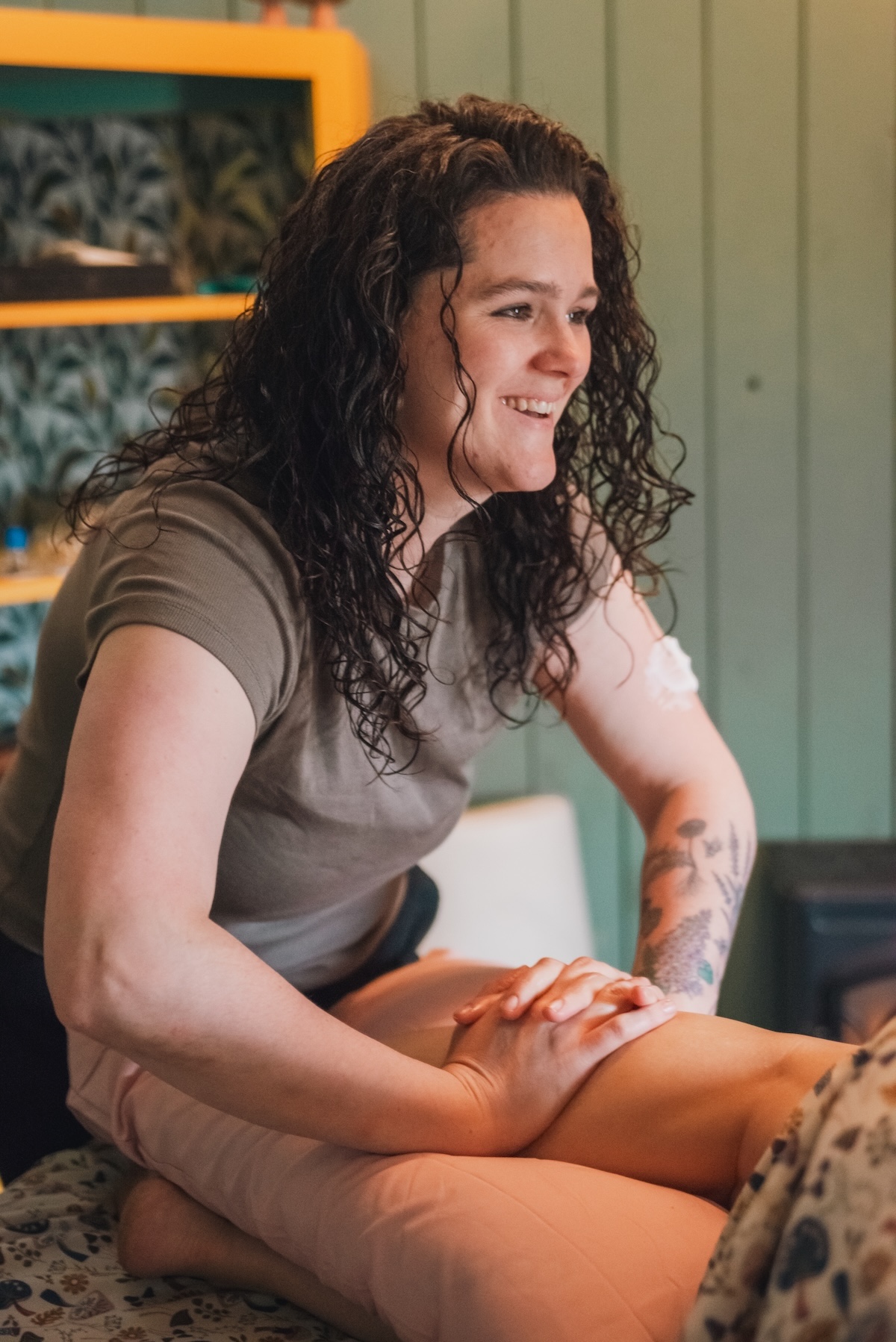massage therapist works leg muscles while smiling
