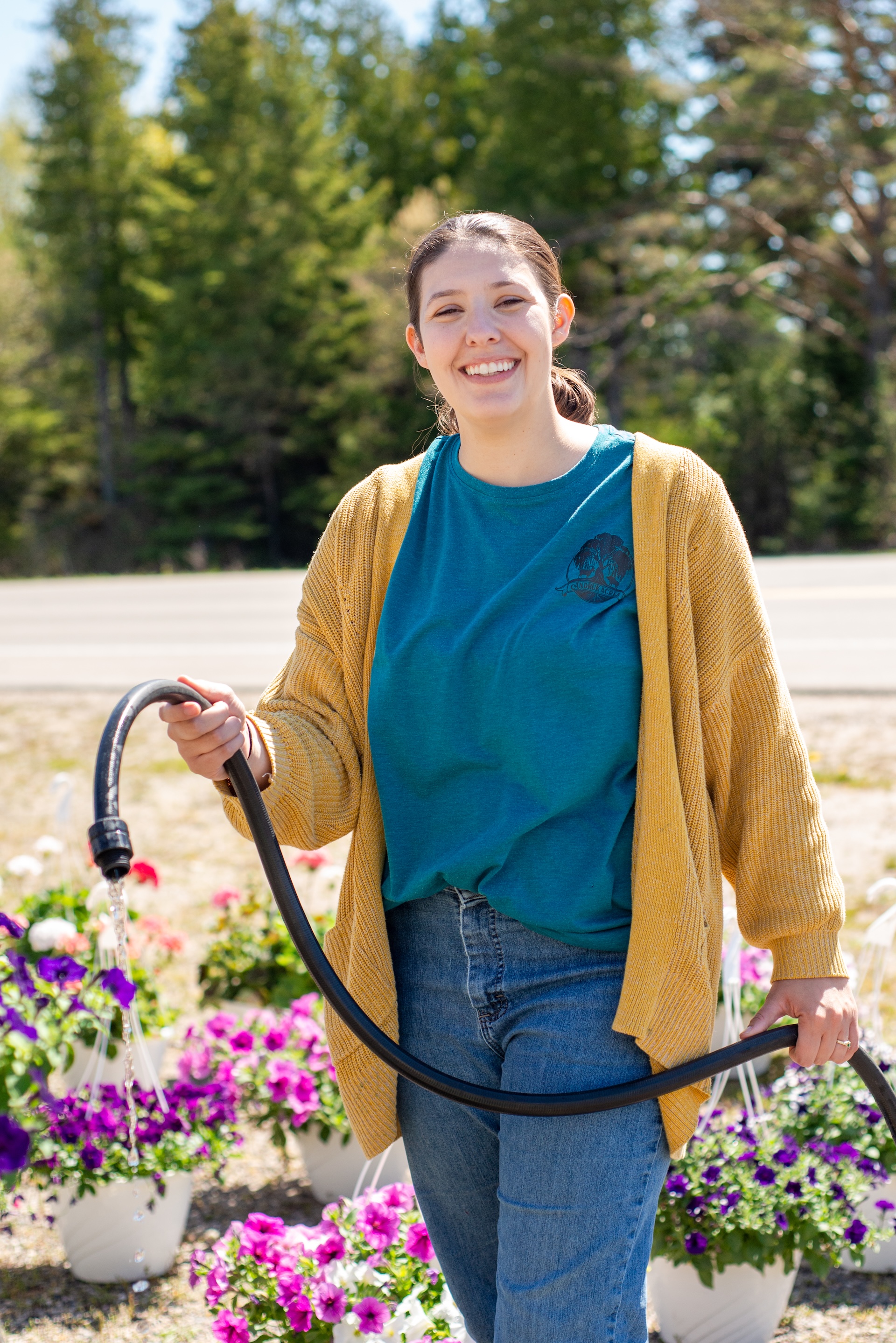 Alison of Andruk Acres watering fresh hanging flower baskets at their Manistique spring market sale