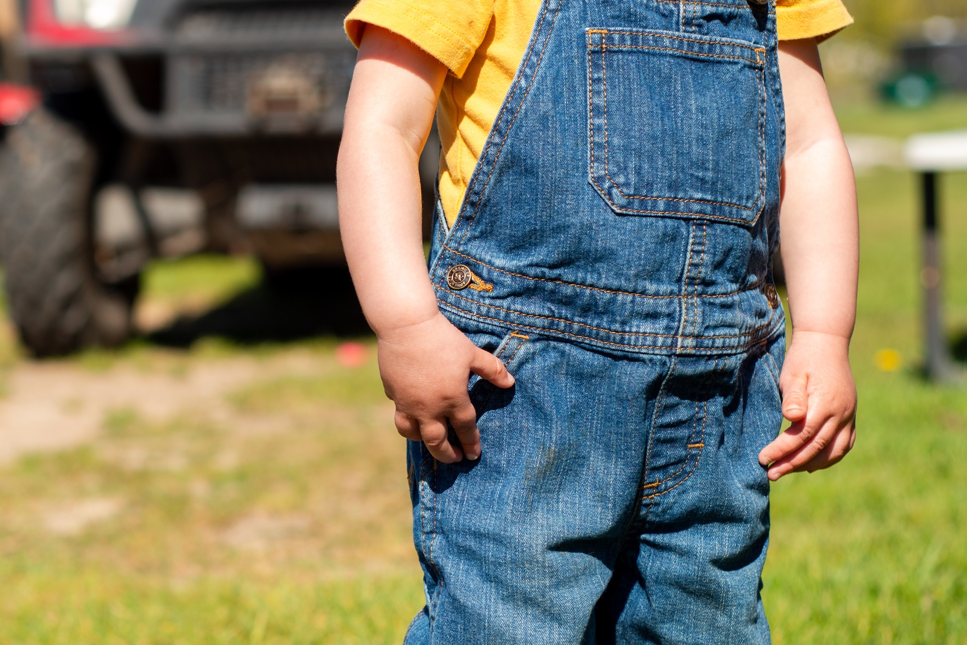 Young girl wearing overalls at a spring outdoor market during a Manistique personal branding photography session