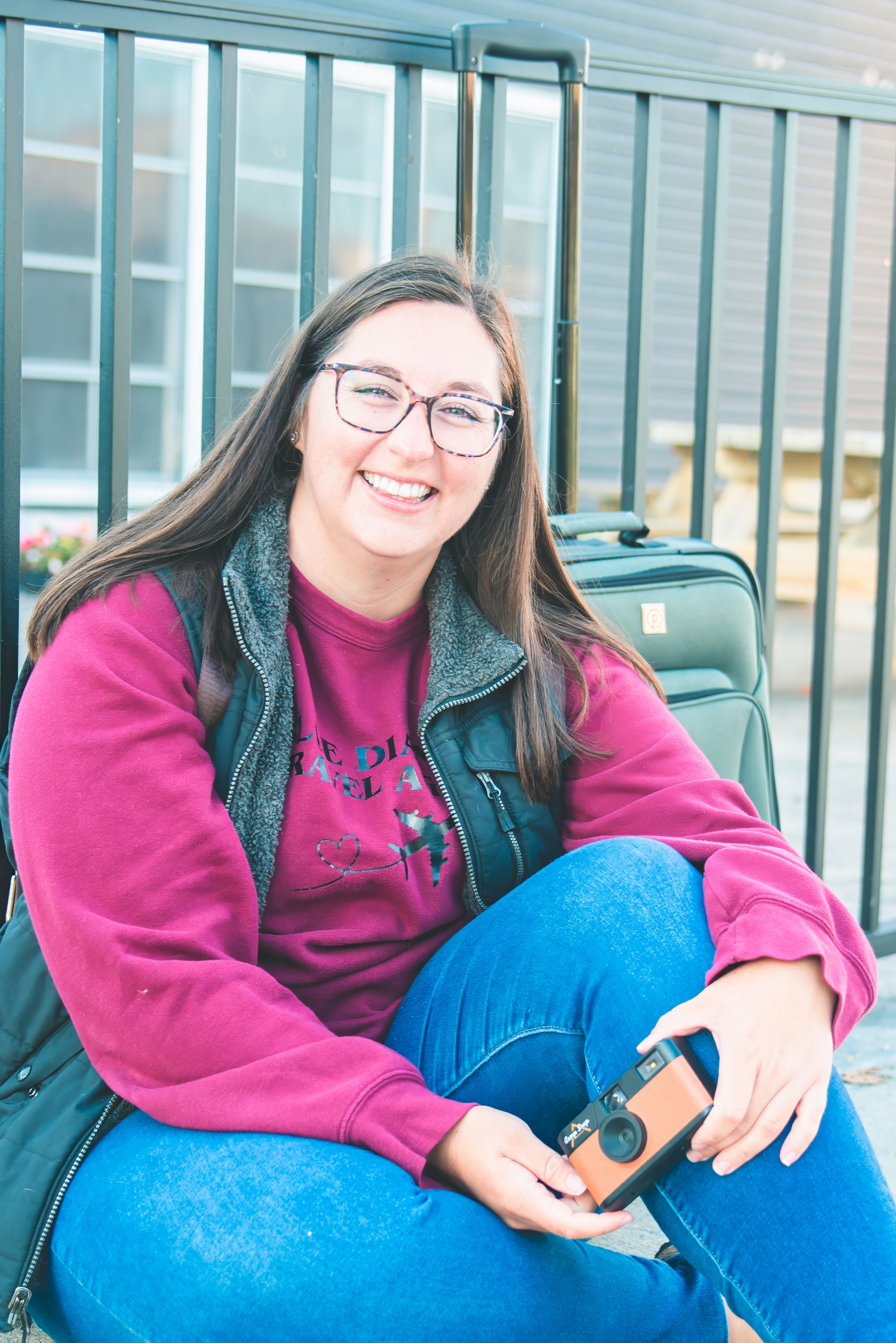 woman sits on sidewalk with suitcase