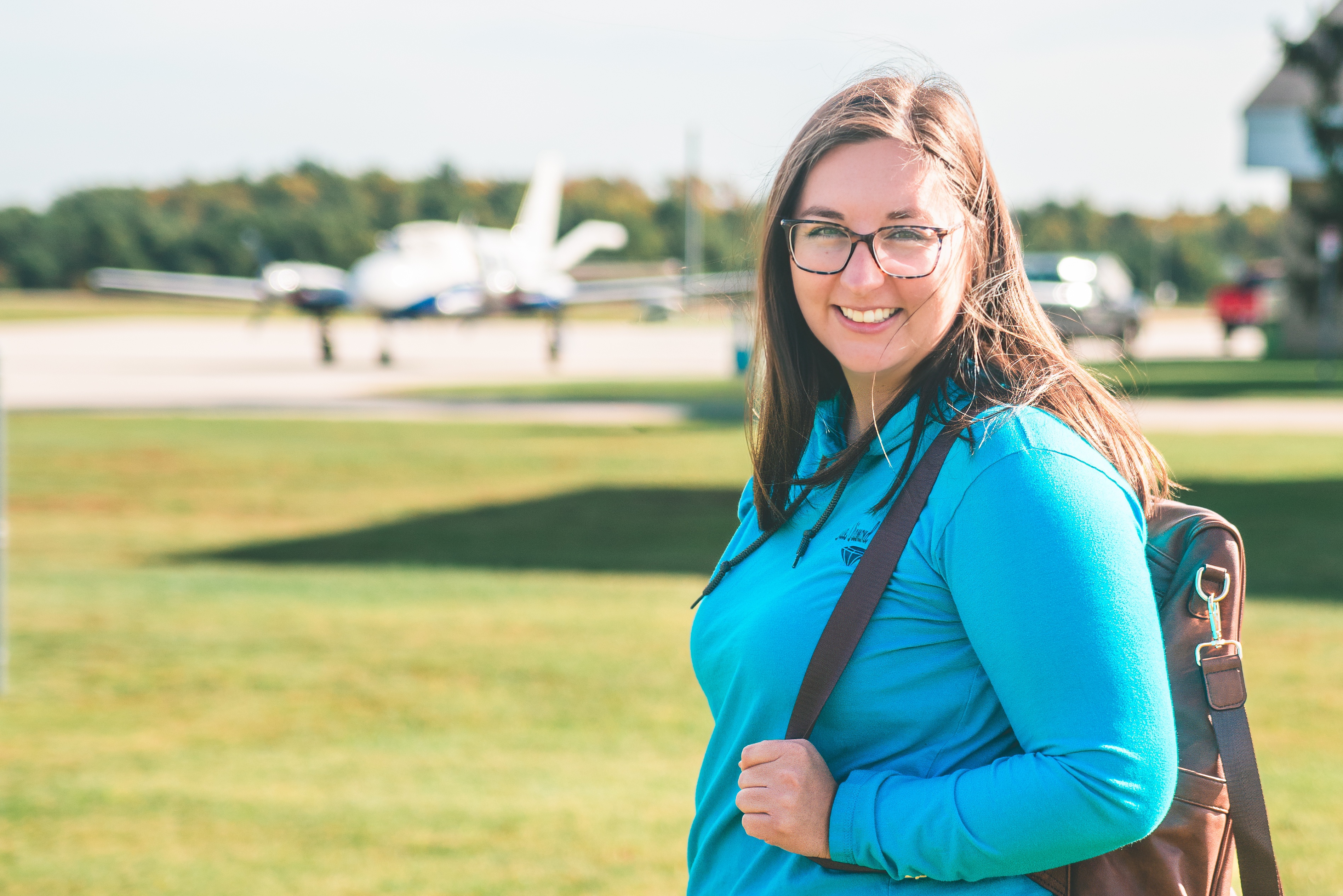 travel agent smiles in front of airplane
