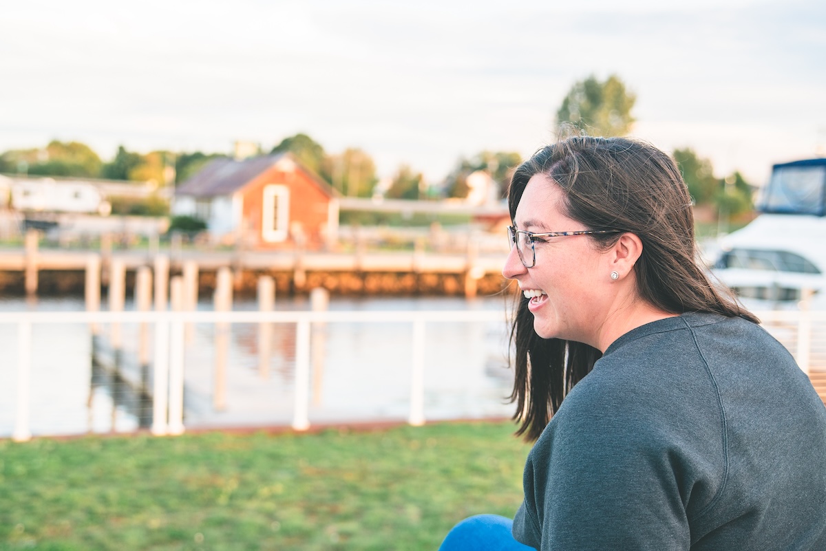 woman smiles in front of lake