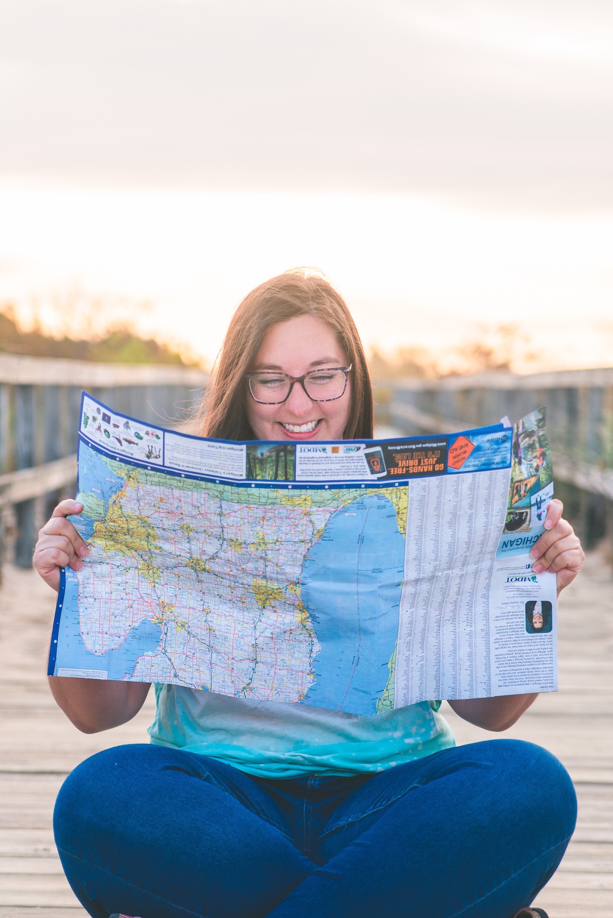woman reads map of michigan on beach