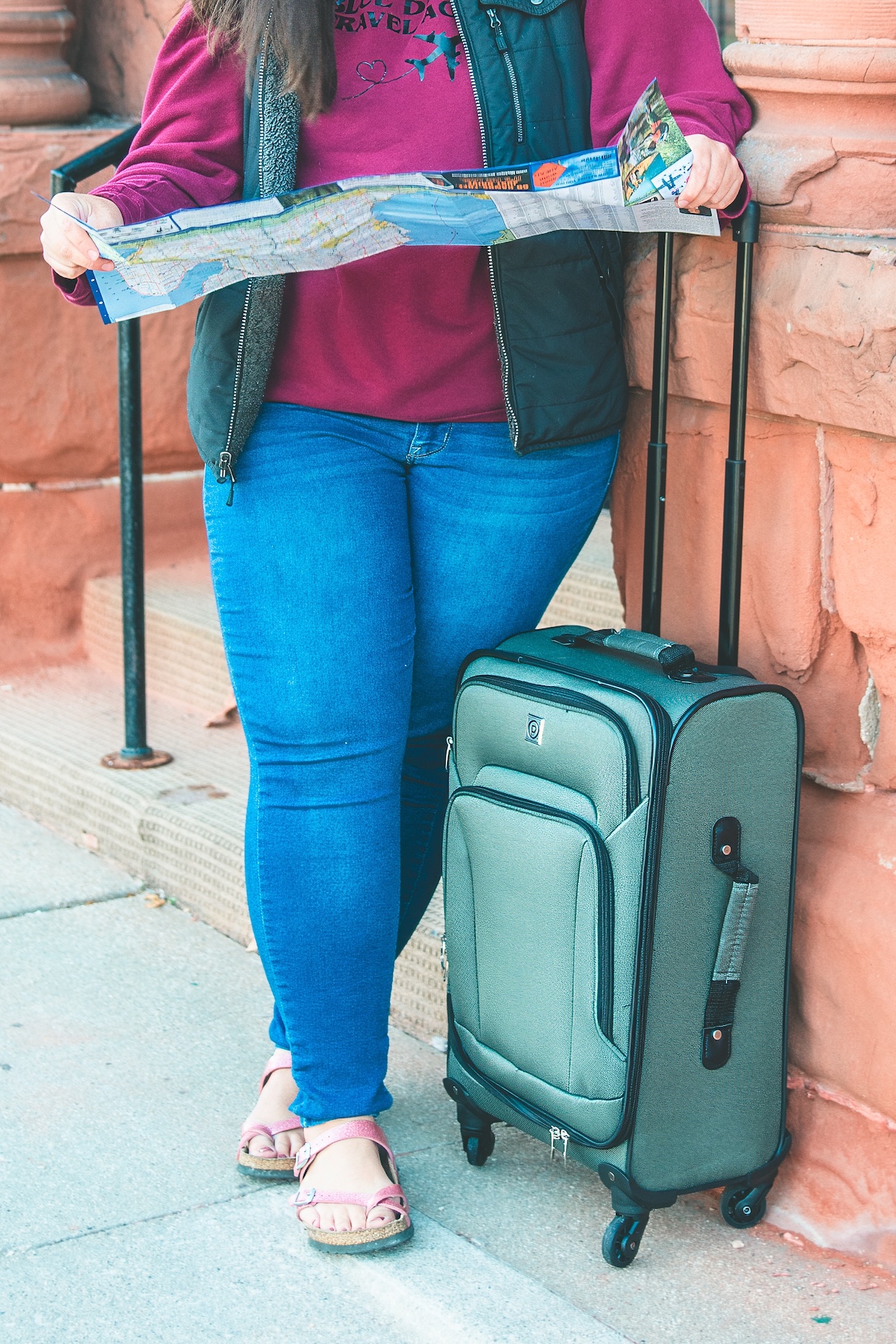 legs of woman with a suitcase and map