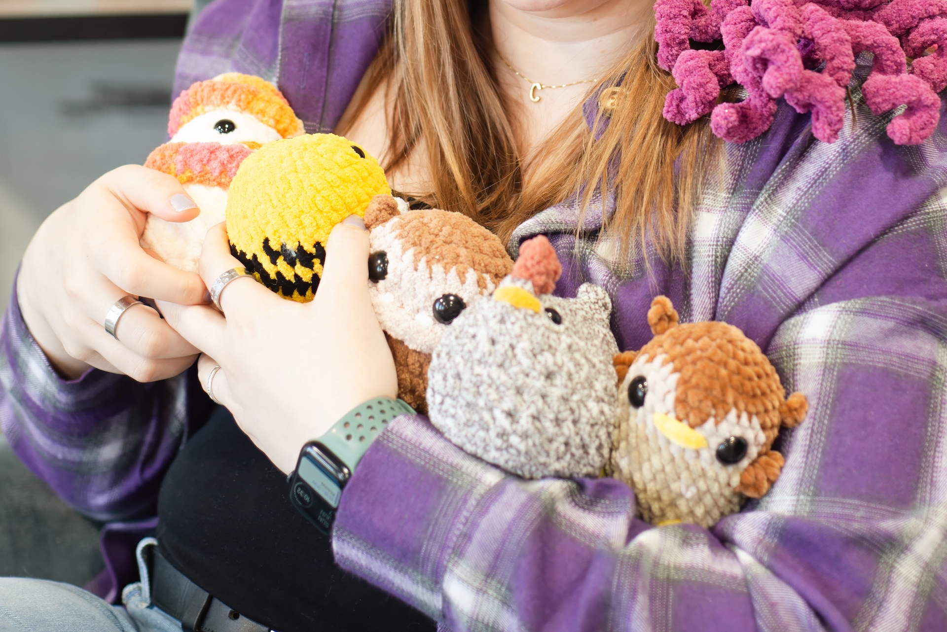 woman holds several assorted crocheted stuffed animals