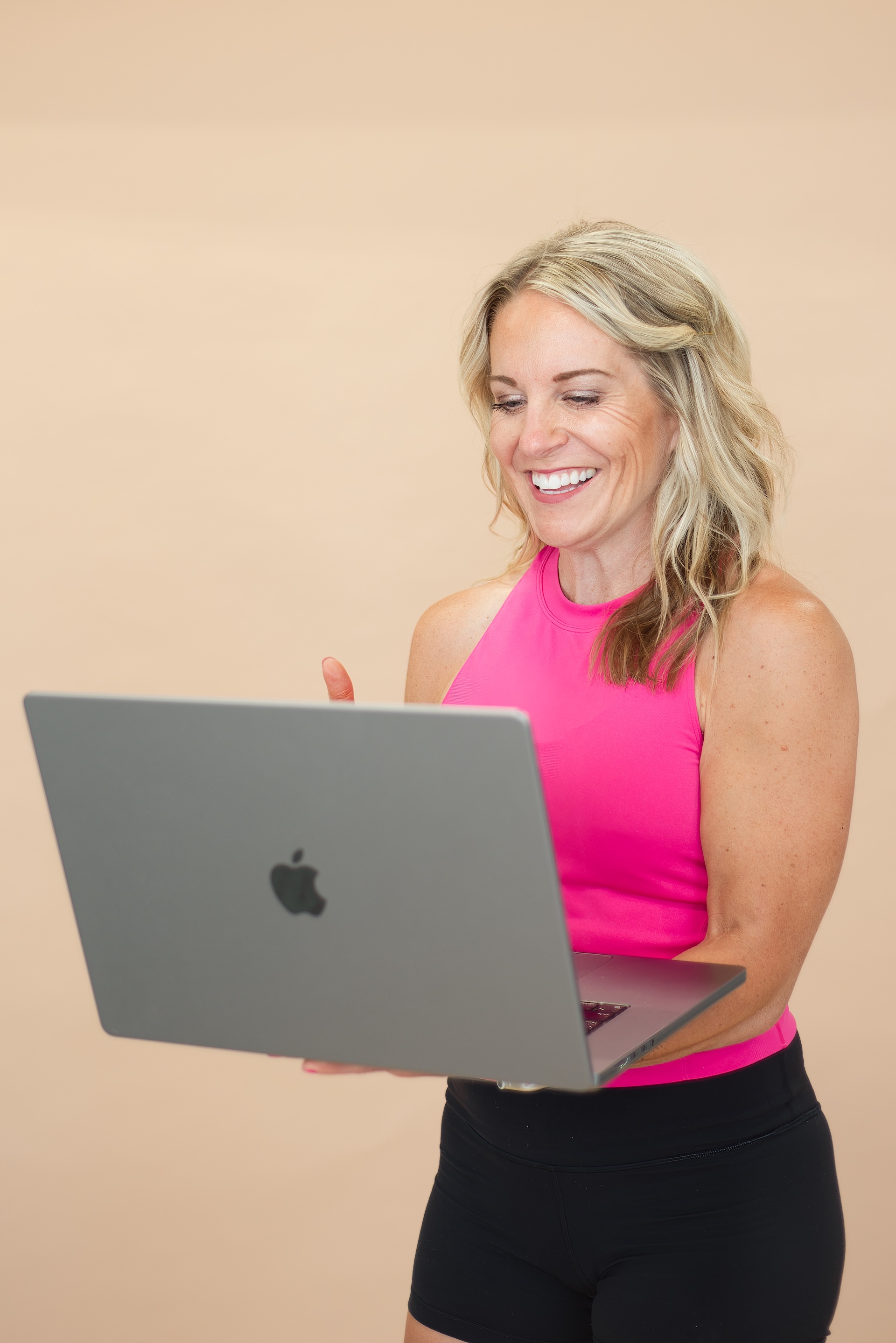 Casey from The Fit Nutritionist holding an open laptop, smiling as she looks down at the screen.