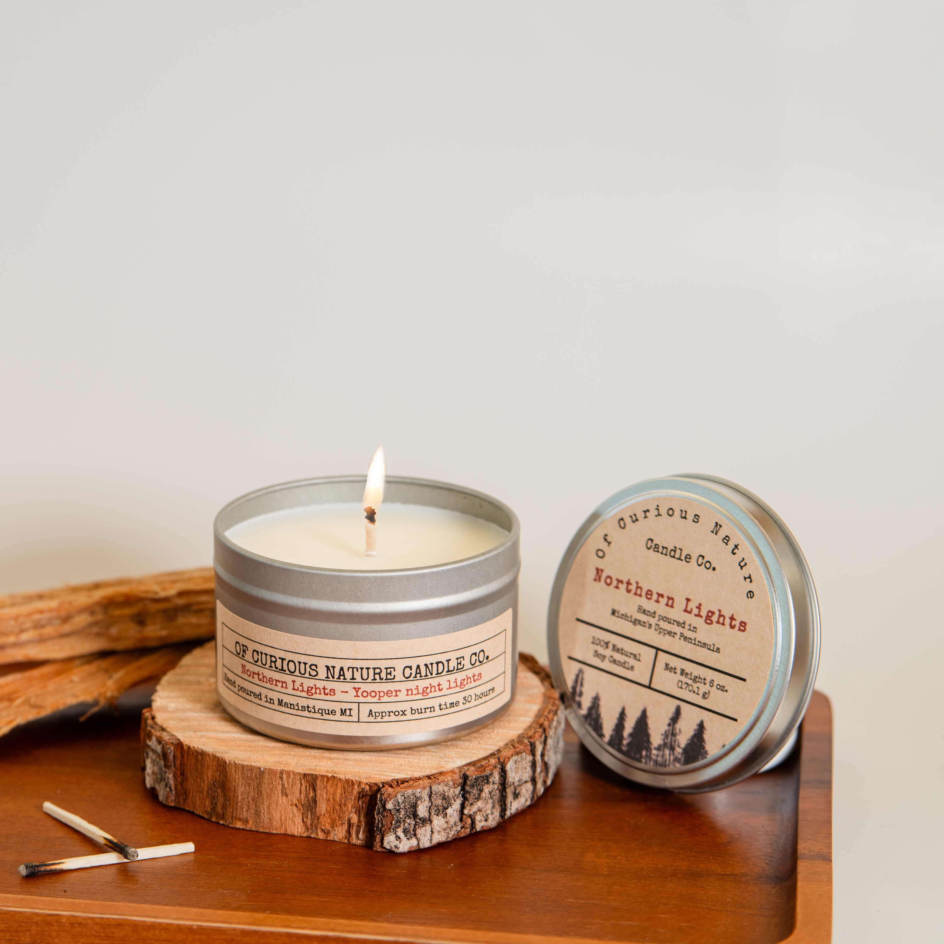 Upper Peninsula themed candle and used matches sit on a tray in front of a white background