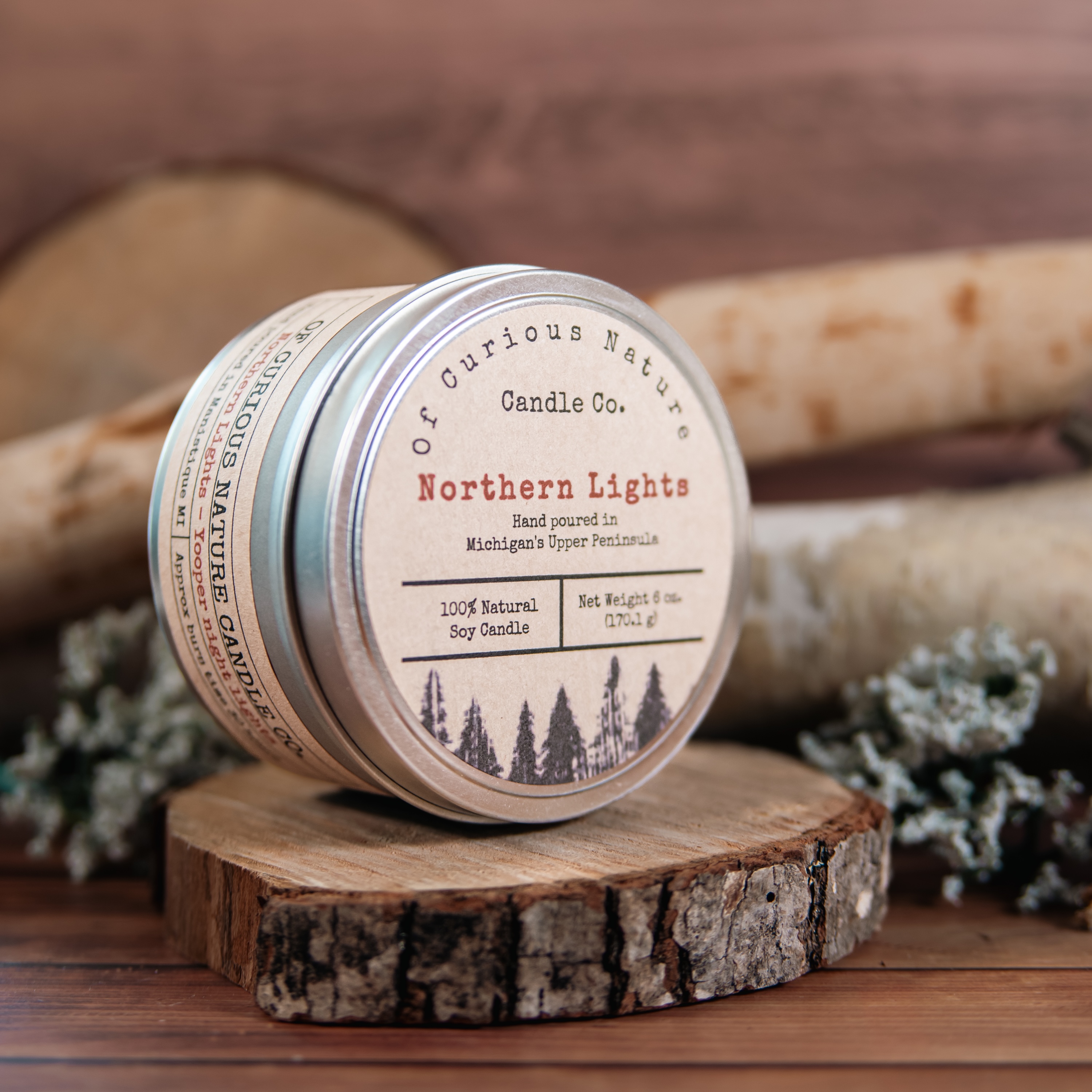 Upper Peninsula themed candle in front of a woodland scene