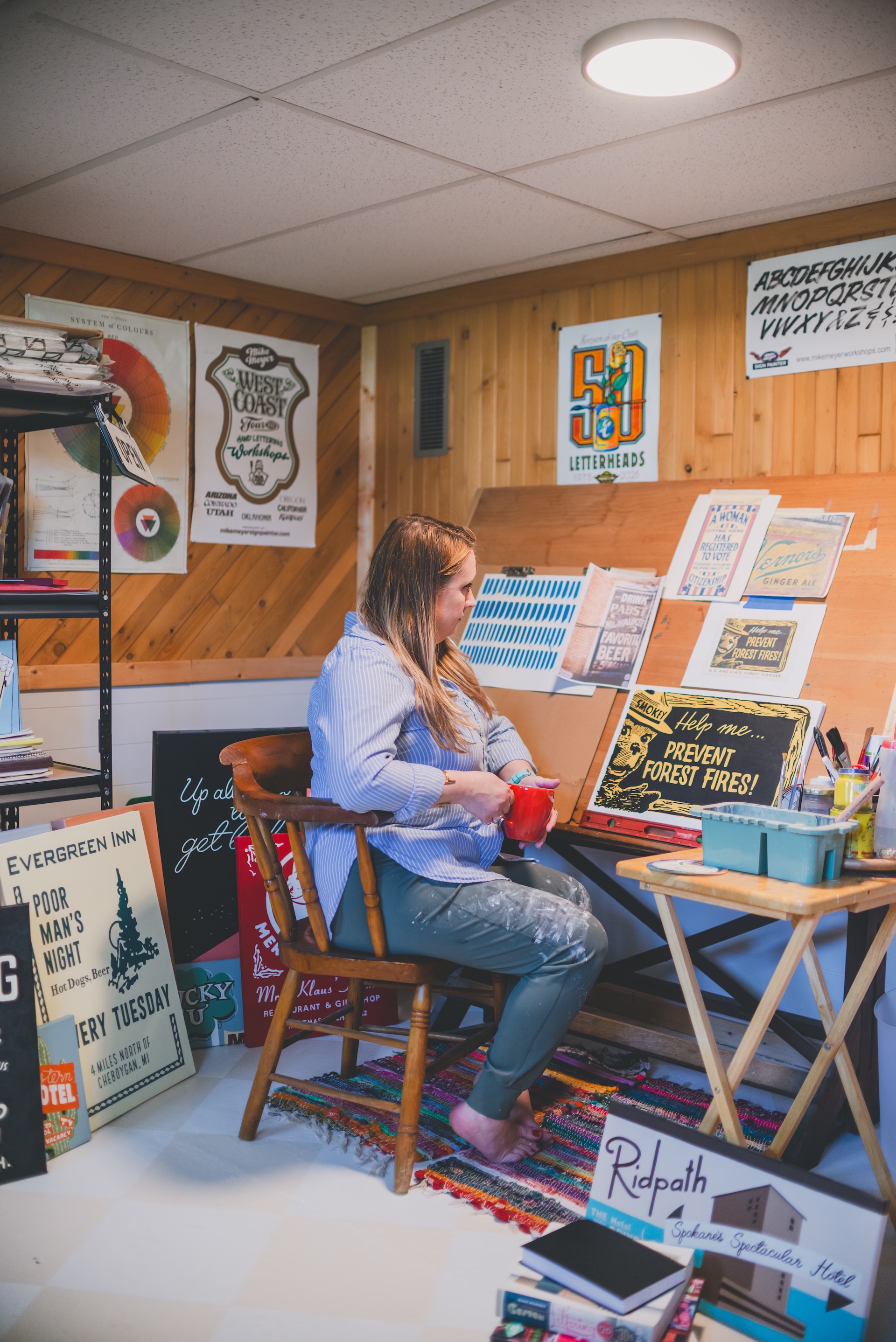 Jamie of Starsiding Studio sits with coffee in her Munising MI art studio
